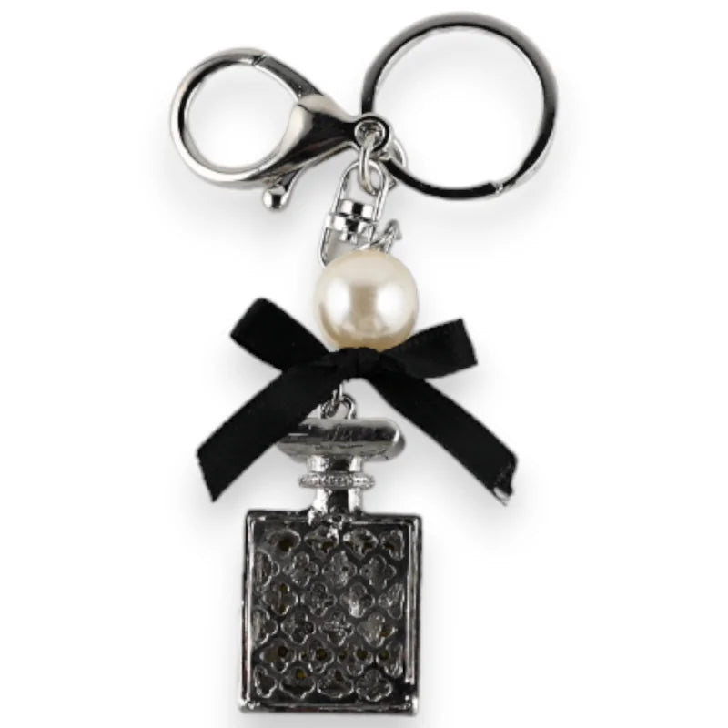 Porte-clés argenté avec pendentif bouteille de parfum, nœud noir et perle blanche