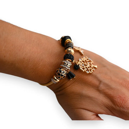 Bracelet charms rigide noir et doré avec pendentif arbre de vie sur poignet féminin