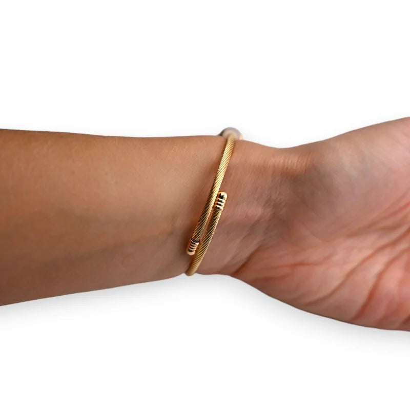 Bracelet jonc doré fin porté au poignet, design minimaliste et élégant